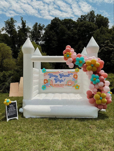 Boho Groovy Birthday Party Bounce House with personalized banner and daisy balloon garden