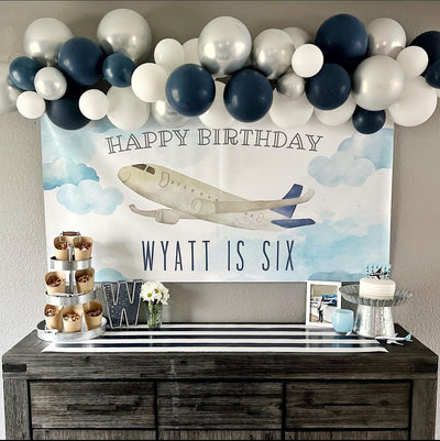 Airplane themed birthday party with personalized banner and blue, white and silver balloon garland