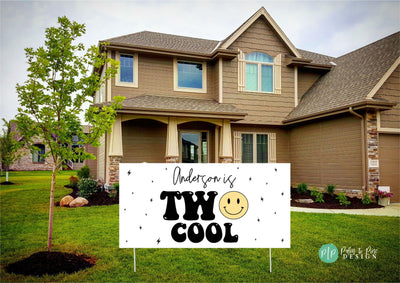 A fun and vibrant &#39;Two Cool&#39; birthday banner featuring a yellow smiley face and striking lightning bolt details in the front yard of a house