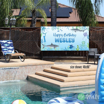 boys shark birthday banner at outdoor party with pool