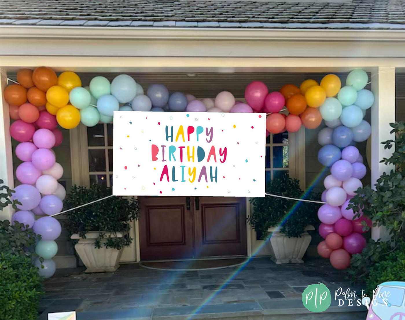 colorful birthday banner and balloon garland in front of house