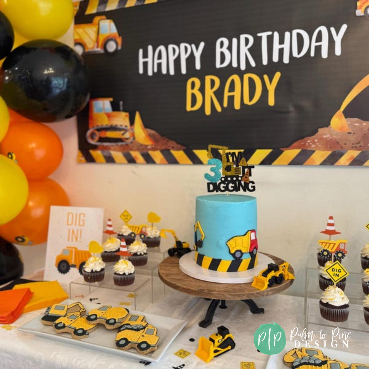 A construction birthday party dessert table with construction cookies, cake and a Dig In Sign and a black and yellow boys birthday party