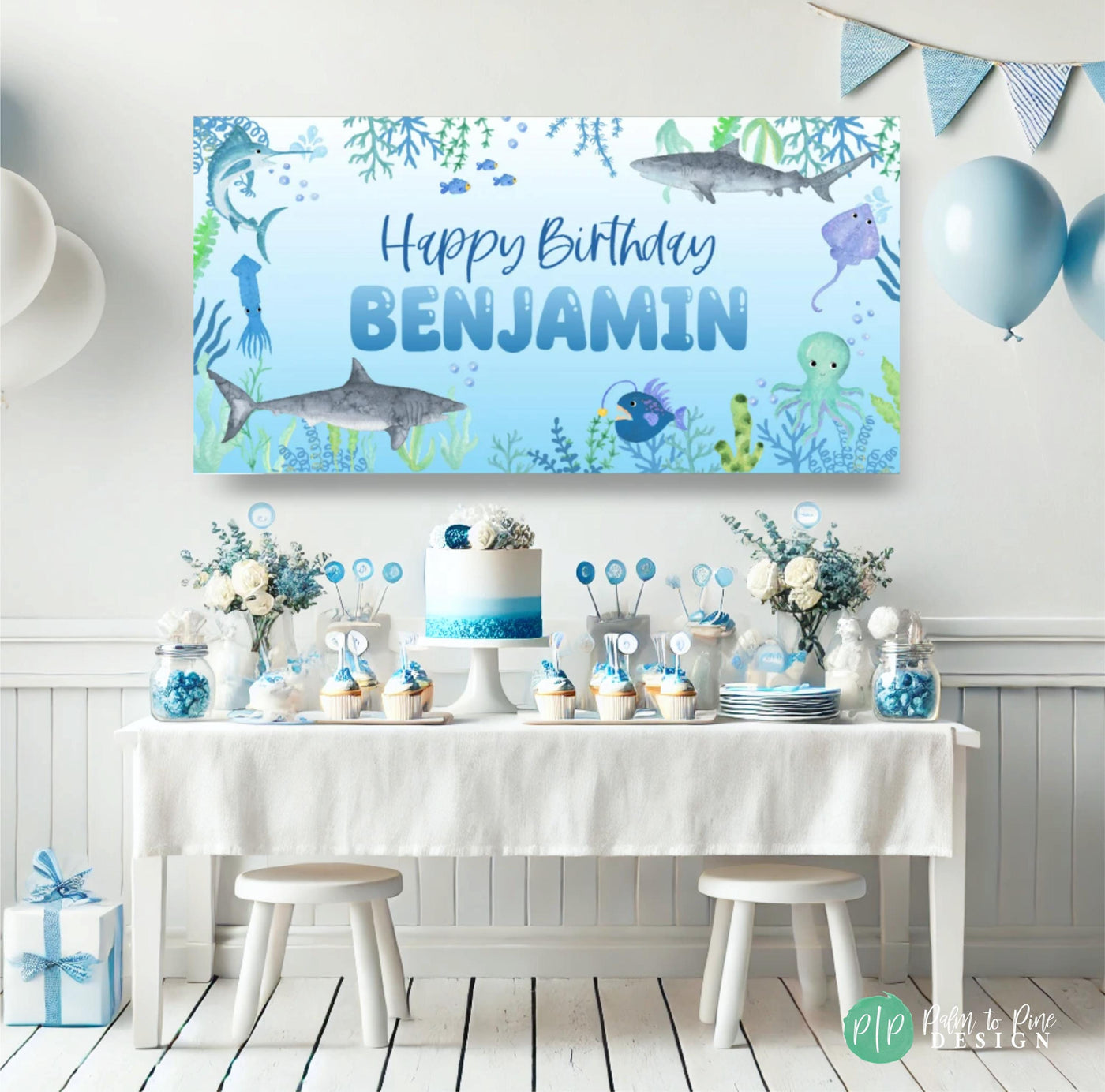 Shark Themed Birthday Banner with Watercolor Ocean Animals in front of a blue and white dessert table