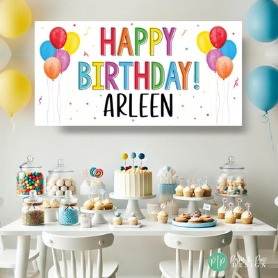 Rainbow-themed personalized birthday banner displayed in a party setup, featuring bold colorful text and festive decor