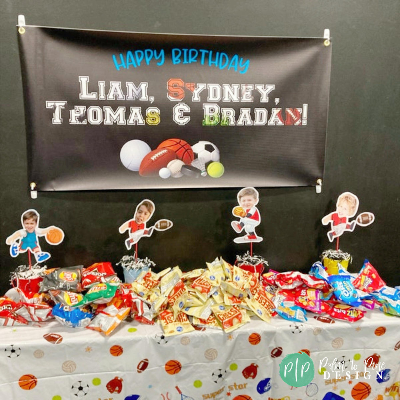 Close-up of a sports-themed birthday banner with sports balls and customizable text in front of snack table